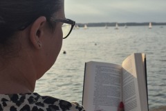 Kobieta czyta ksiązkę na tle jeziora