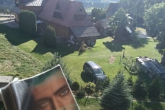 Książka na tle zielonego krajobrazu i chaty w stylu góralskim